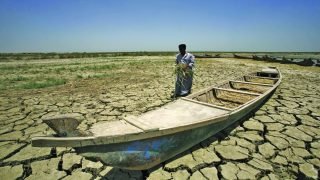 An Iraqi man walks past a canoe siting on dry, cracked earth in the Chibayish marshes near the southern Iraqi city of Nasiriyah on June 25, 2015. Marsh areas in southern Iraq have been affected since the Islamic State group started closing the gates of a dam on the Euphrates River in the central city of Ramadi, which is under the jihadist group's control. AFP PHOTO / HAIDAR HAMDANI (Photo credit should read HAIDAR HAMDANI/AFP/Getty Images)